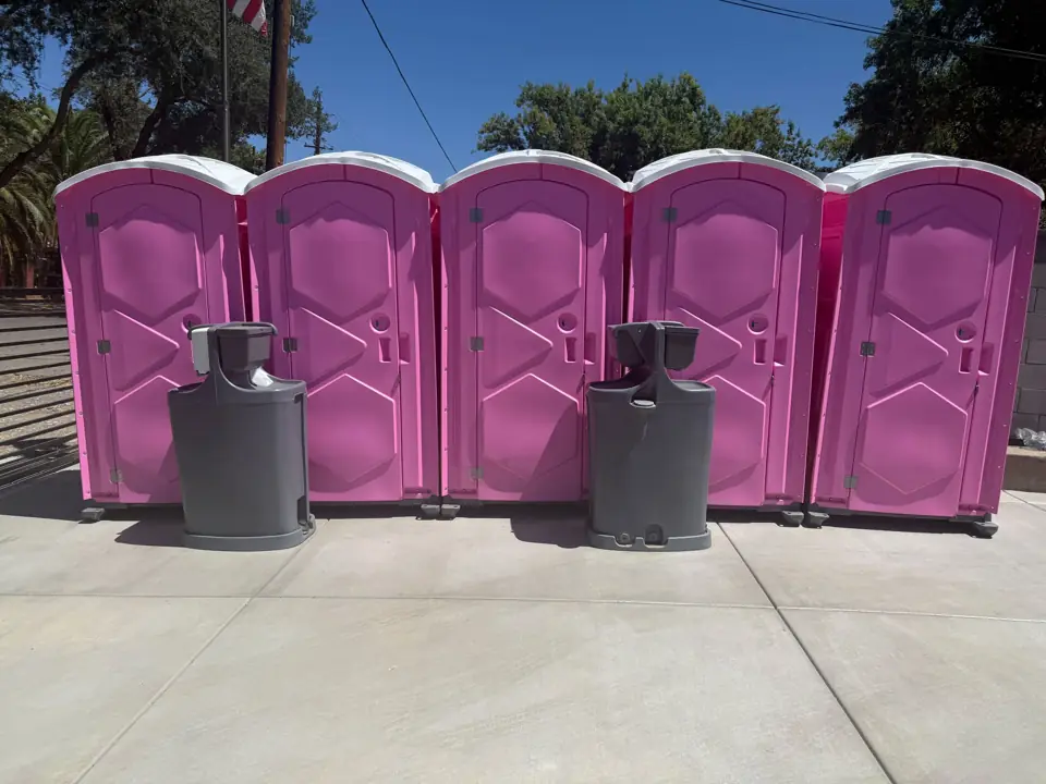 Row of pink event porta potties with two hand-wash stations in front