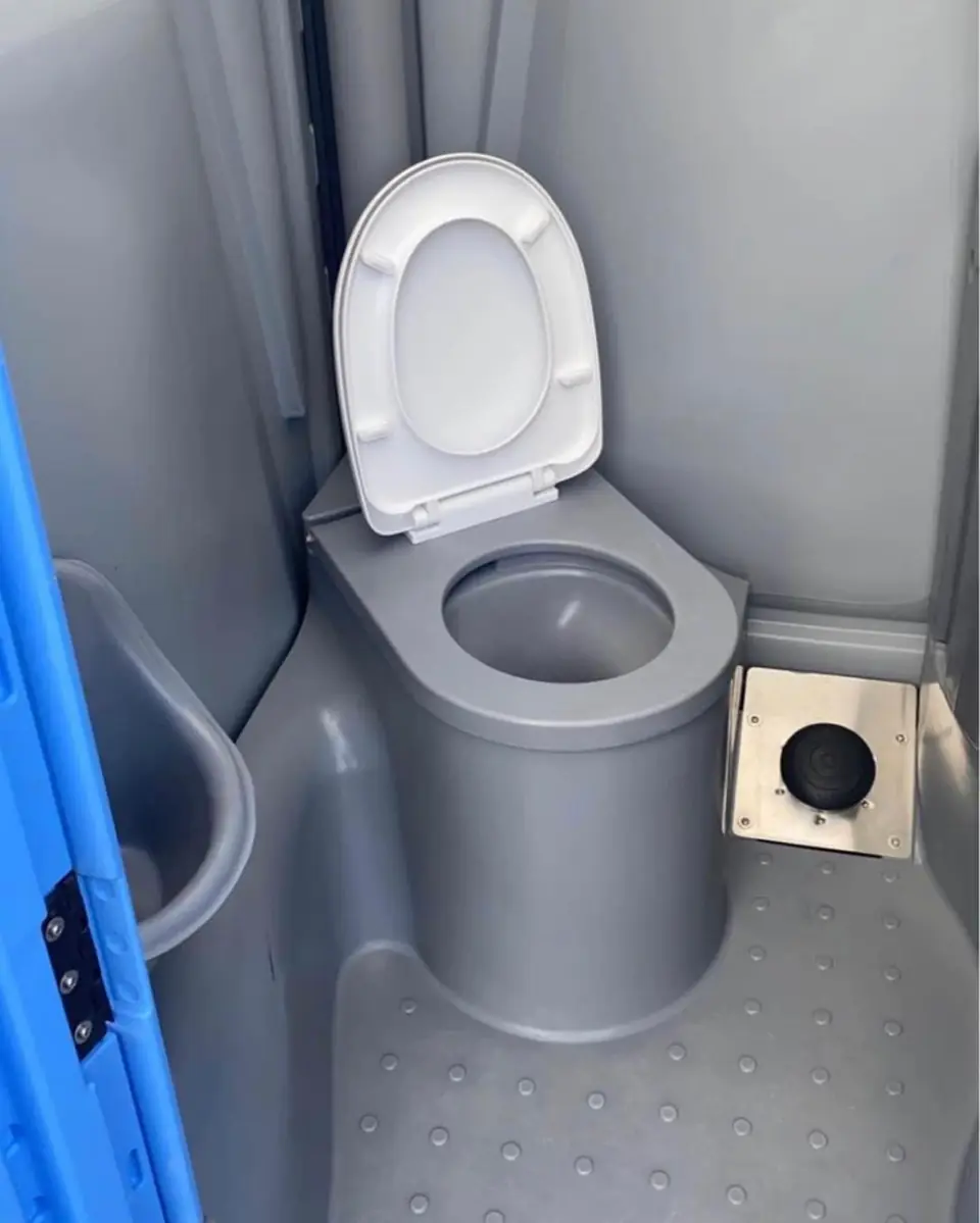 Flushing porta potty seat with foot pump inside a gray unit