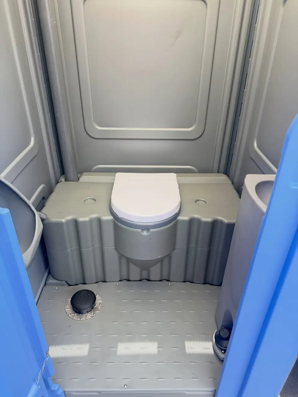 Inside a standard porta potty showing the seat and floor